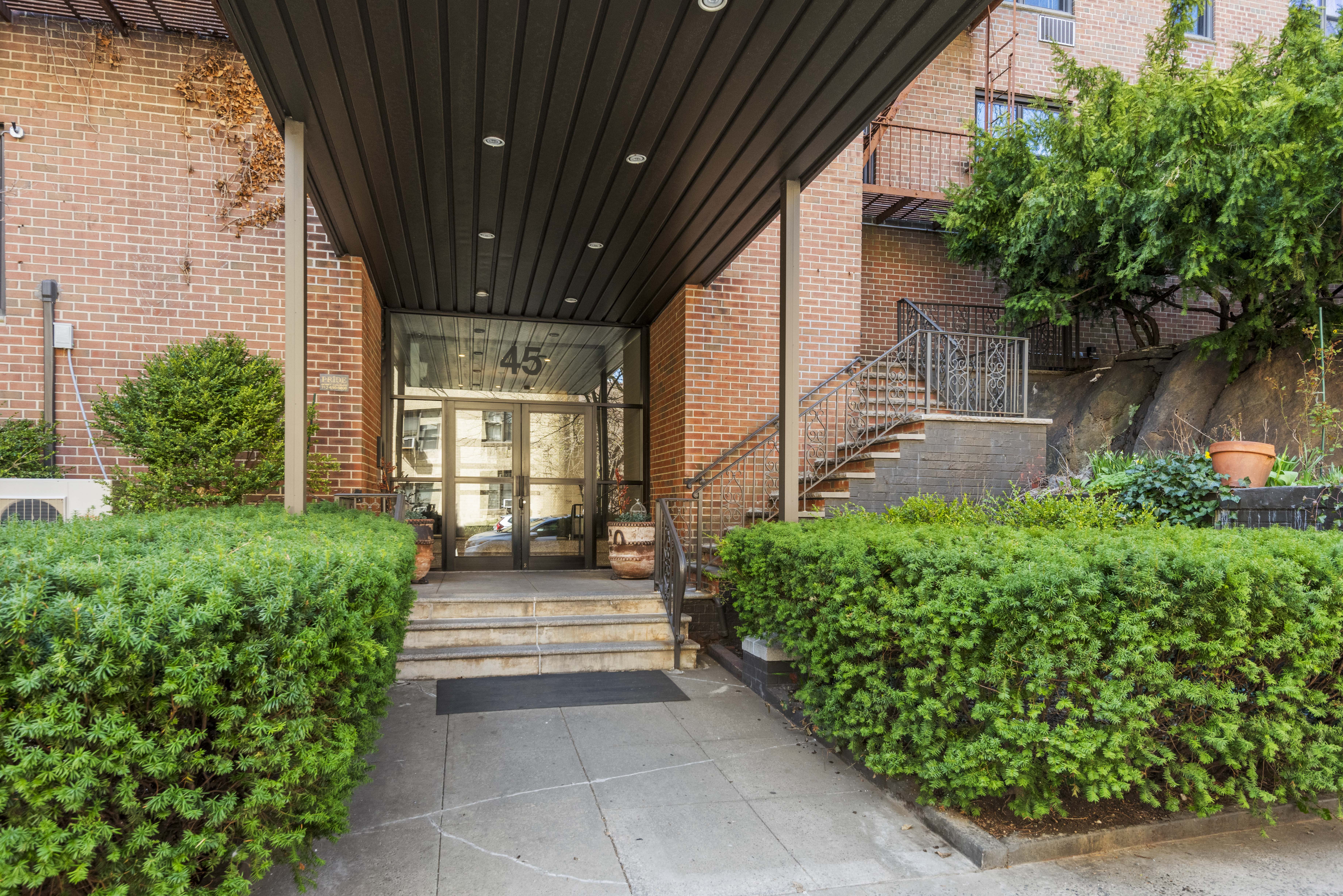 45 Overlook Terrace, Unit 7J Manhattan, NY 10033 - Photo 10 of 11 a view of a pathway of a house with potted plants and a large tree