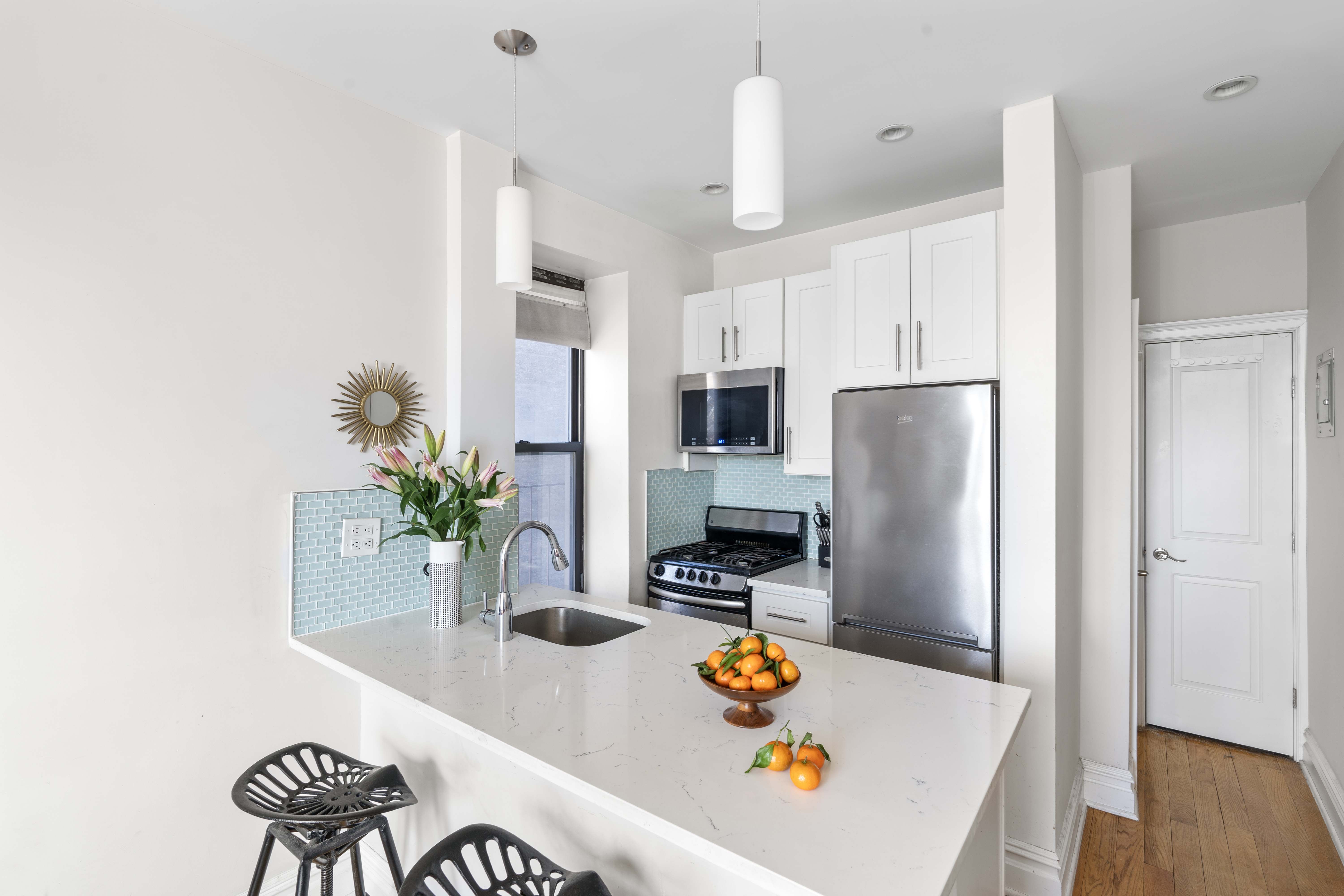 660 Riverside Drive, Unit 2A Manhattan, NY 10031 - Photo 4 of 6 a kitchen with stainless steel appliances potted plants and wooden floor