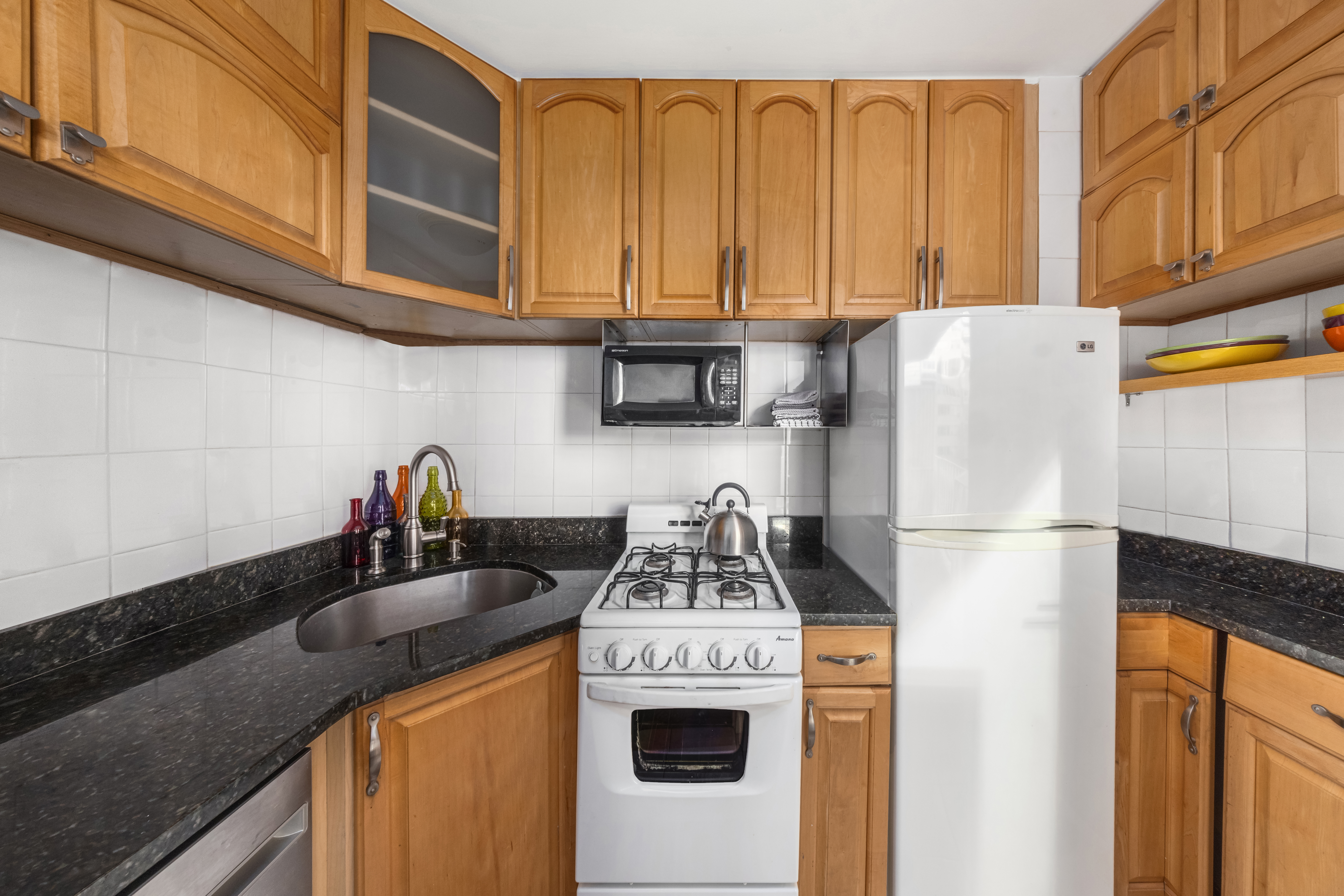 1160 3rd Avenue, Unit 6BC Manhattan, NY 10065 - Photo 8 of 13 a kitchen with stainless steel appliances granite countertop a refrigerator a stove a sink dishwasher and white cabinets with wooden floor