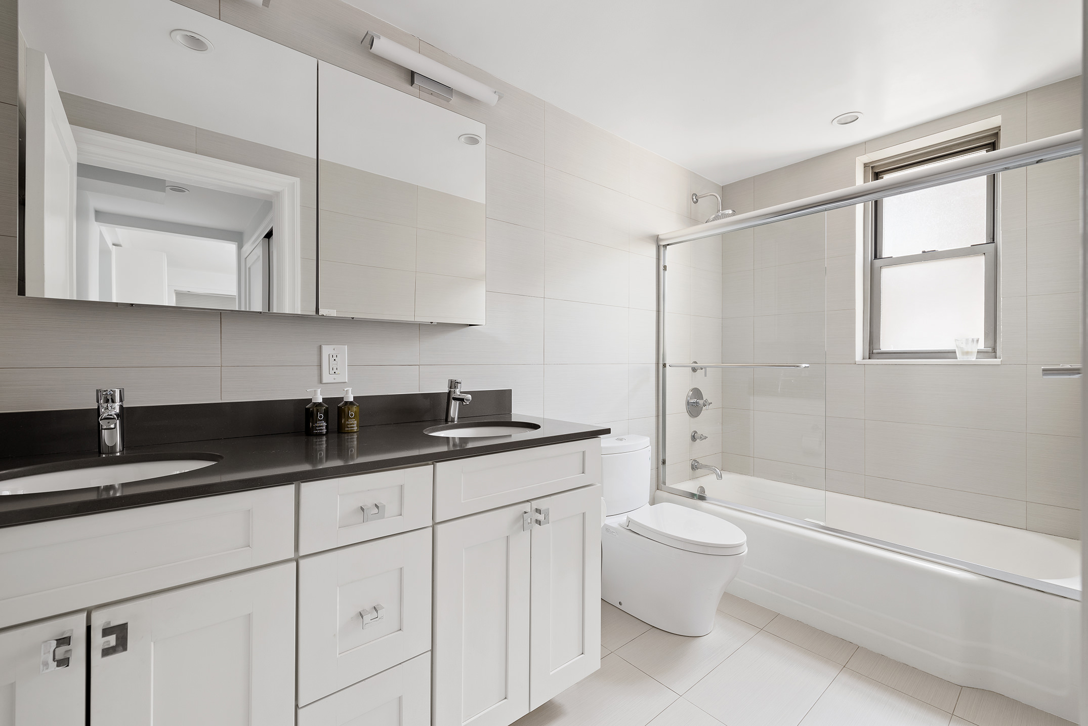 136 East 76th Street, Unit 16DE Manhattan, NY 10021 - Photo 8 of 14 a bathroom with a granite countertop sink a toilet a mirror and bathtub
