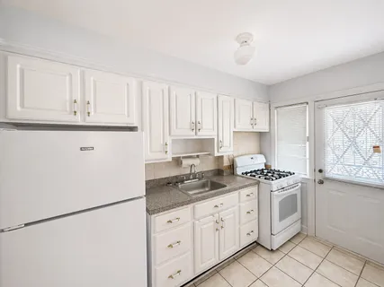 a kitchen with granite countertop white cabinets and white appliances