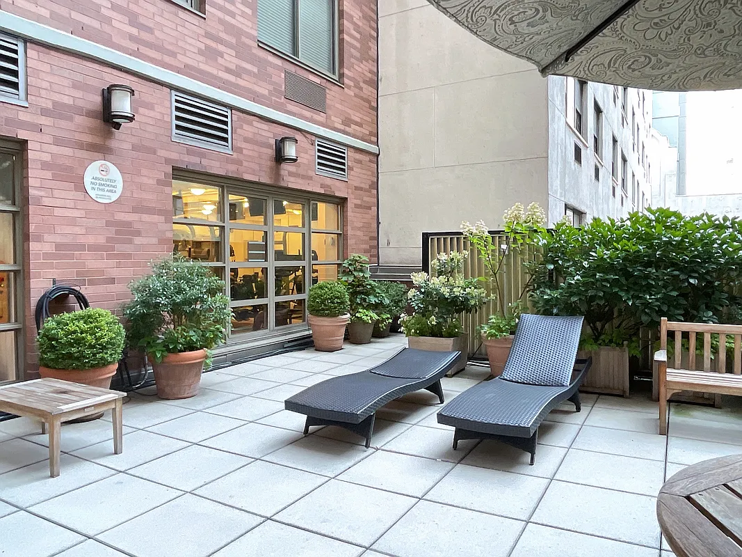 400 East 90th Street, Unit 15B Manhattan, NY 10128 - Photo 12 of 15 a view of a patio with table and chairs potted plants and a bench