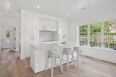 a kitchen with a stove a sink a refrigerator and wooden floor