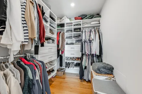 a view of walk in closet with clothes and shoes