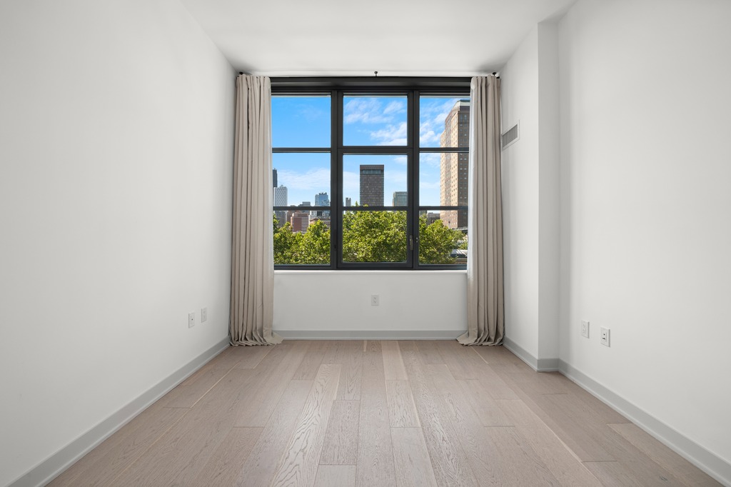 115 York Street, Unit 4J Brooklyn, NY 11201 - Photo 7 of 9 an empty room with wooden floor and windows