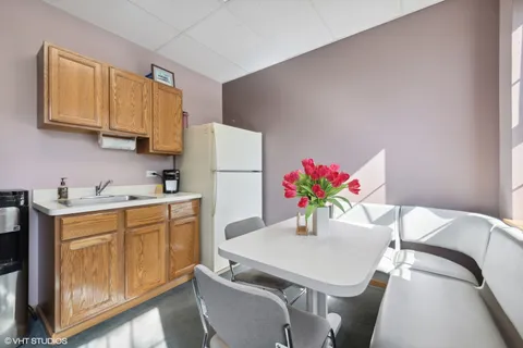 a kitchen with stainless steel appliances a white table chairs and a refrigerator