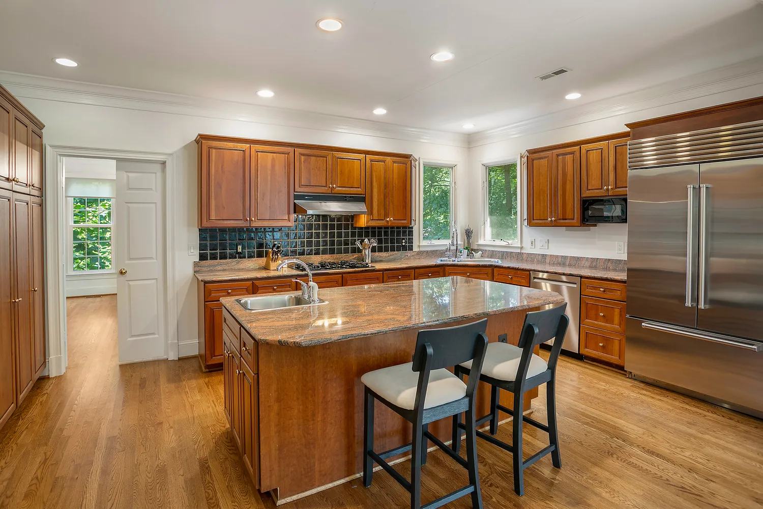 a kitchen with stainless steel appliances granite countertop a sink a stove a refrigerator and island with wooden floor