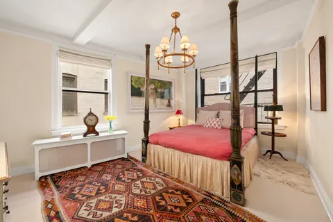 a bed room with a bed a chandelier and a window