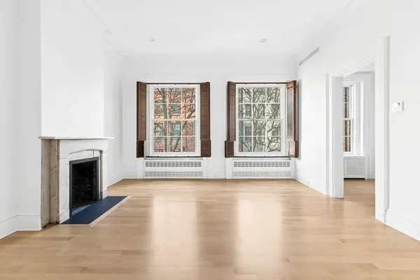 a view of an empty room with exposed radiator and fireplace