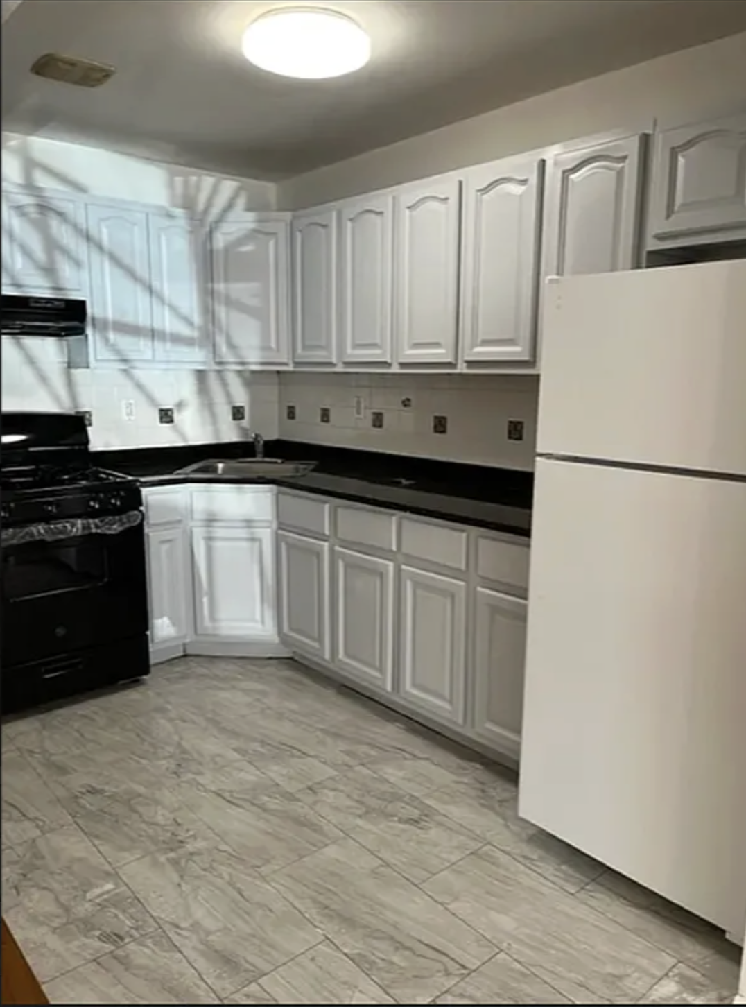 a kitchen with white cabinets and refrigerator