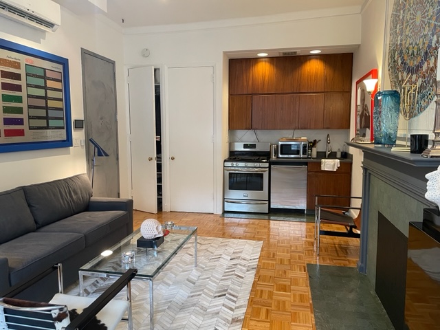 128 East 62nd Street, Unit 4F Manhattan, NY 10065 - Photo 3 of 9 a living room with furniture a rug and a fireplace