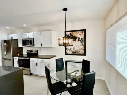 a kitchen with stainless steel appliances kitchen island granite countertop a stove a refrigerator a sink a dining table and chairs with wooden floor