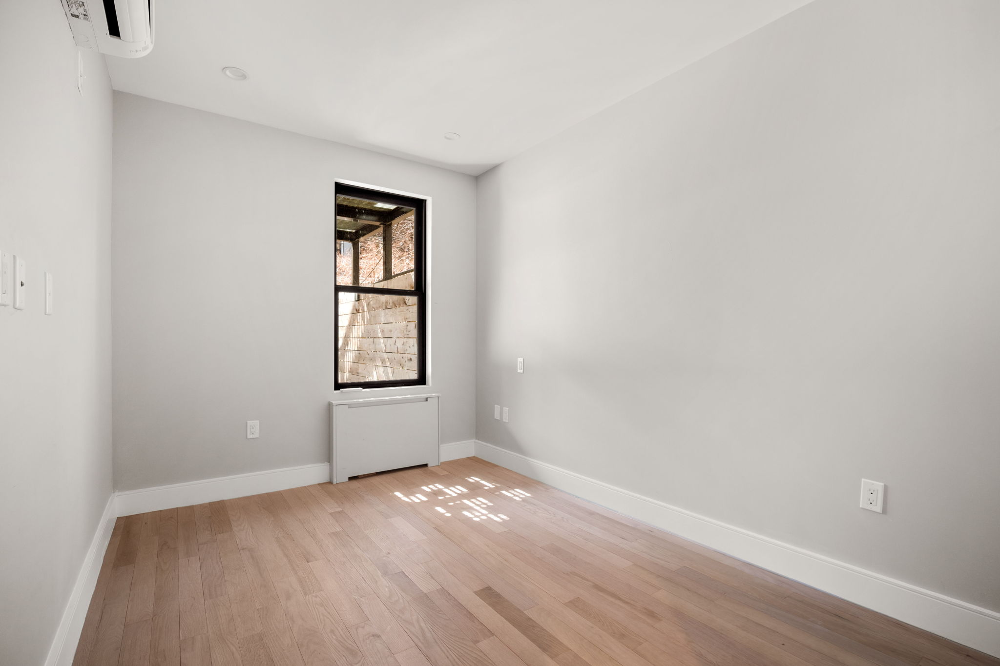 916 Greene Avenue, Unit 1 Brooklyn, NY 11221 - Photo 7 of 9 an empty room with wooden floor and windows