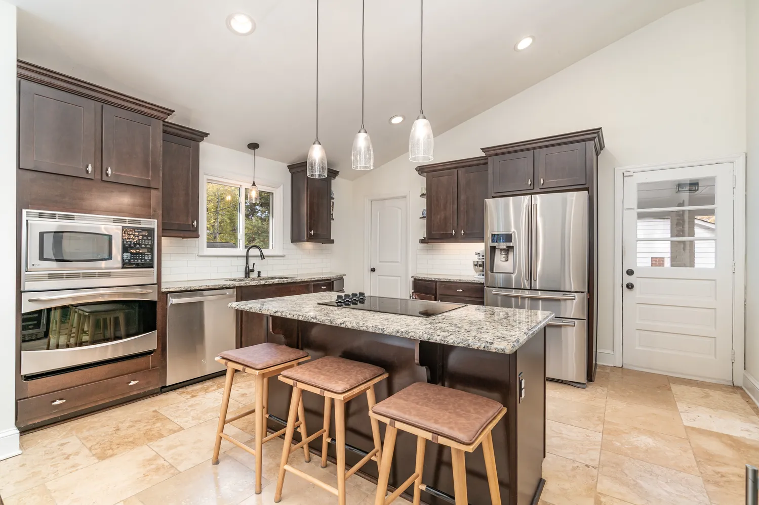 a kitchen with stainless steel appliances kitchen island granite countertop a stove refrigerator and cabinets