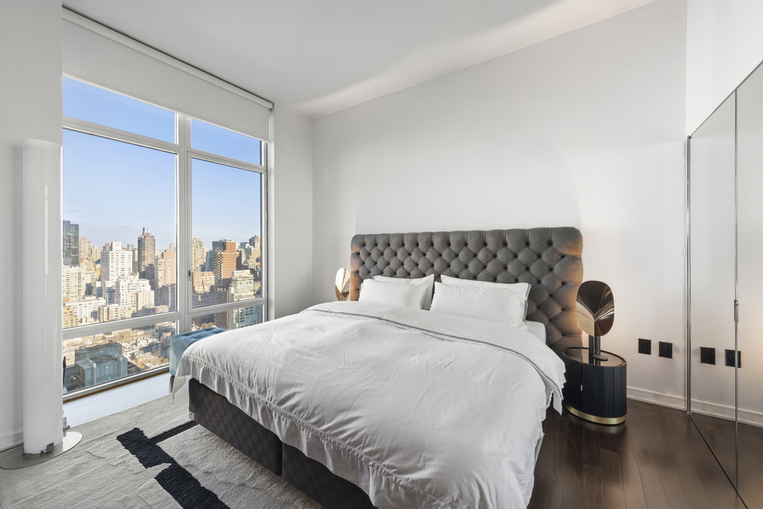 207 East 57th Street, Unit 34A Manhattan, NY 10022 - Photo 10 of 22 a bedroom with a bed and wooden floor