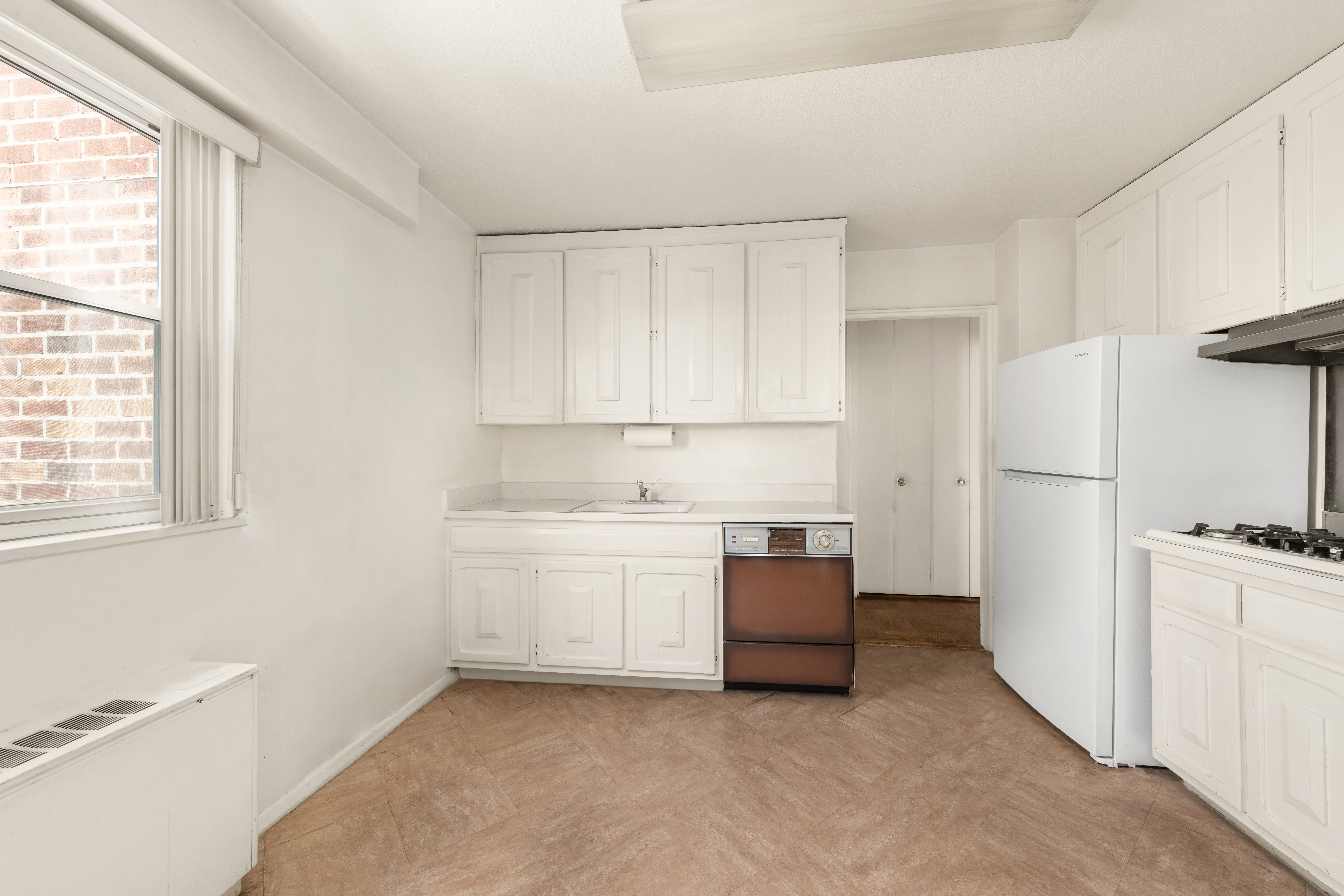 70-31 108th Street, Unit 14H Queens, NY 11375 - Photo 4 of 8 a kitchen with white cabinets and white appliances