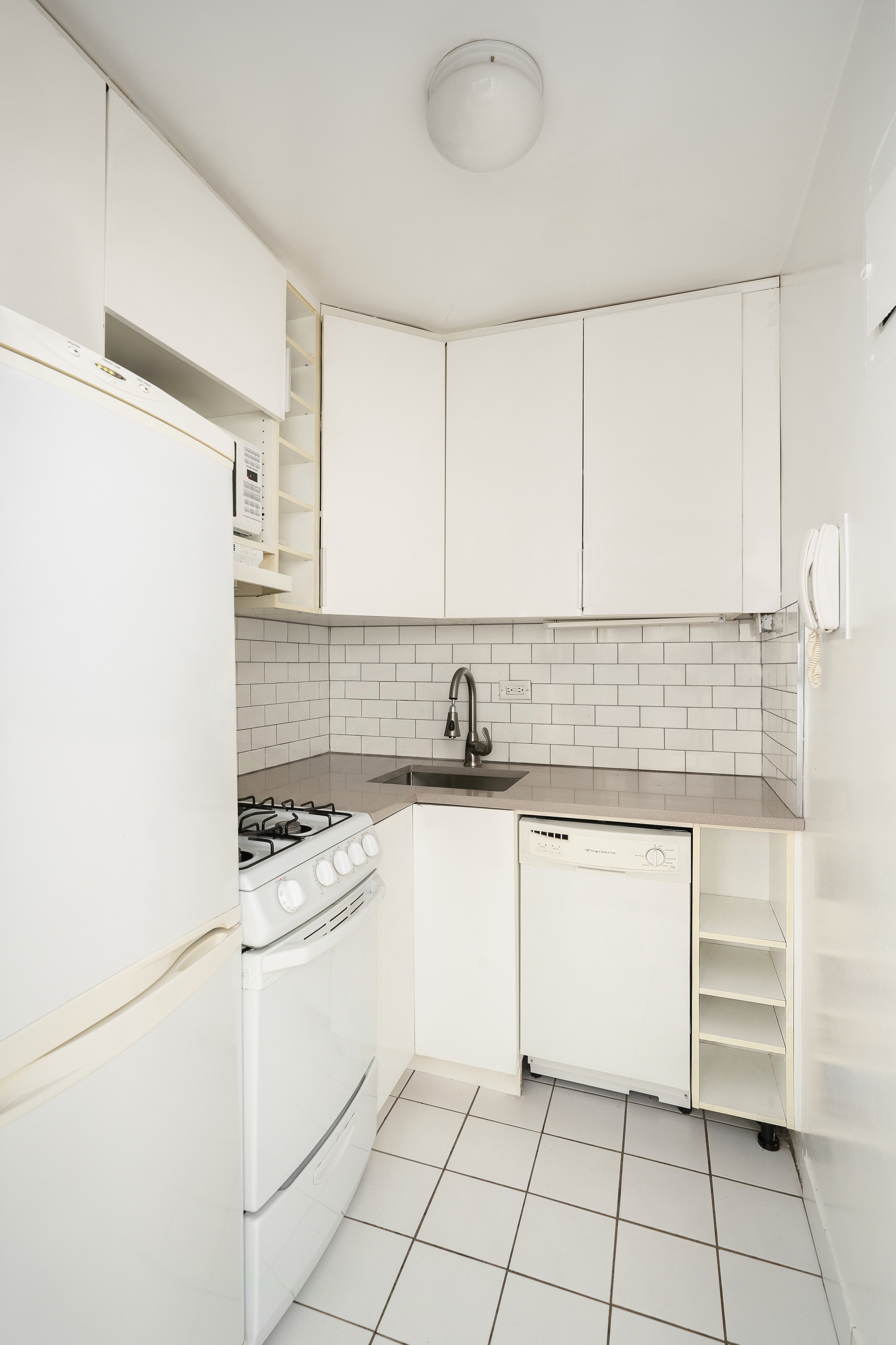411 East 53rd Street, Unit 10E Manhattan, NY 10022 - Photo 4 of 8 a kitchen with white cabinets appliances and sink