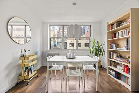 a view of a dining room with furniture a book and wooden floor
