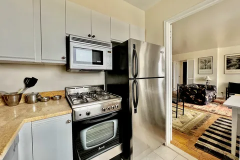 a kitchen with stainless steel appliances granite countertop a refrigerator stove and white cabinets