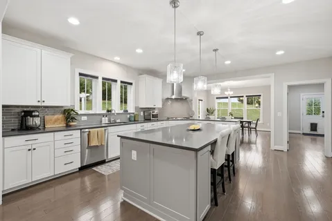 a large kitchen with lots of counter space a sink appliances and living room view