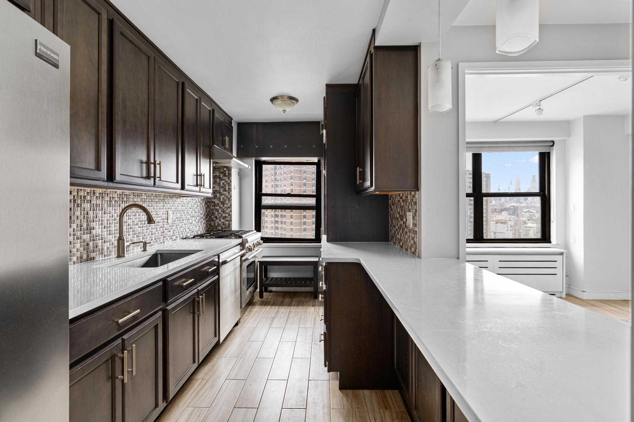 266 East Broadway, Unit 1304B Manhattan, NY 10002 - Photo 3 of 8 a kitchen with stainless steel appliances granite countertop a sink stove and cabinets