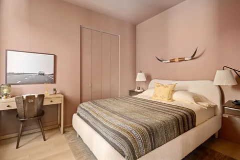 a bedroom with a bed a chair and painting on the wall