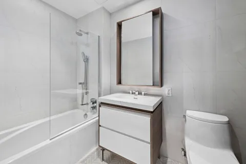 a bathroom with a toilet sink vanity tub and mirror