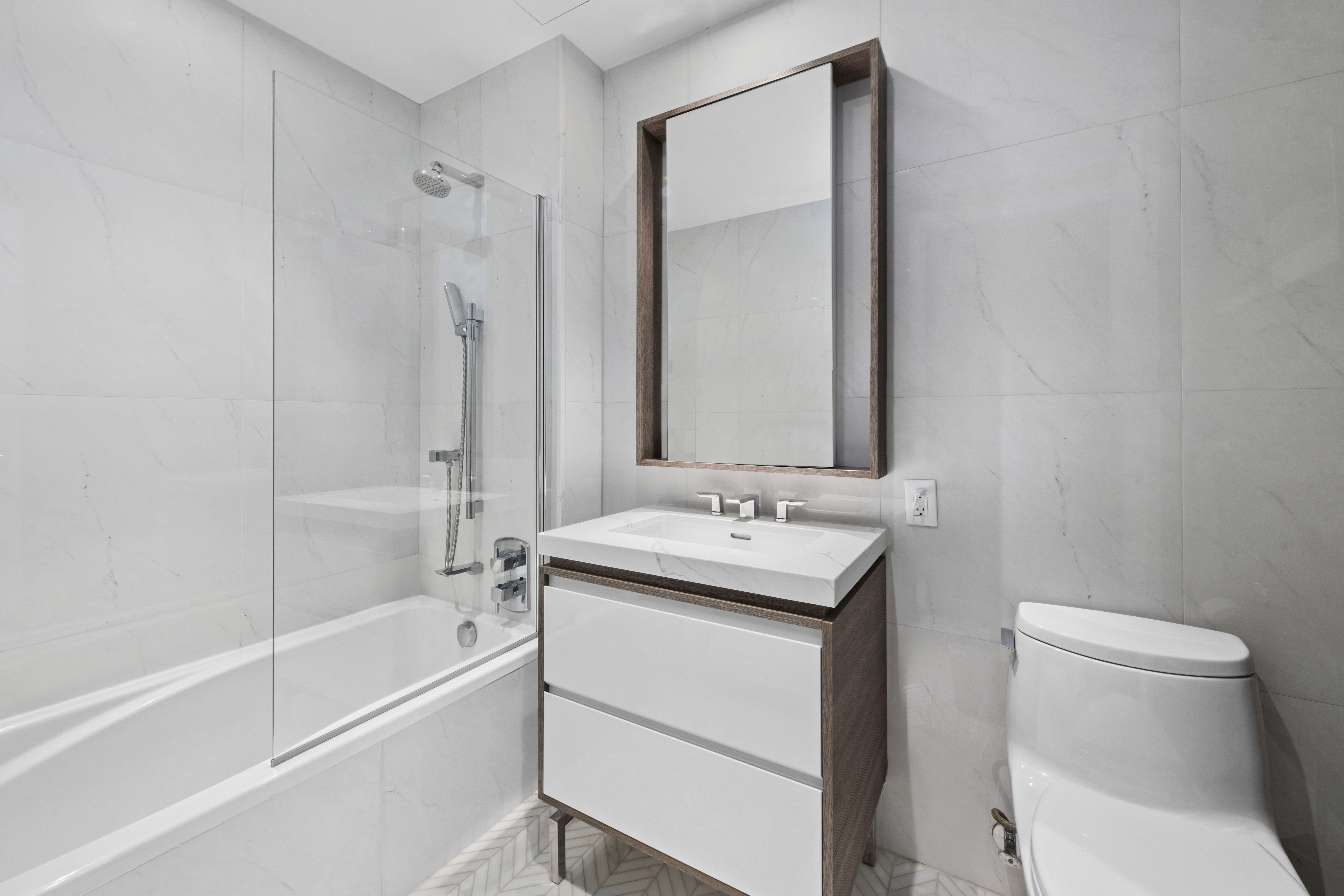 505-513 West 43rd Street, Unit 6K Manhattan, NY 10036 - Photo 7 of 16 a bathroom with a toilet sink vanity tub and mirror