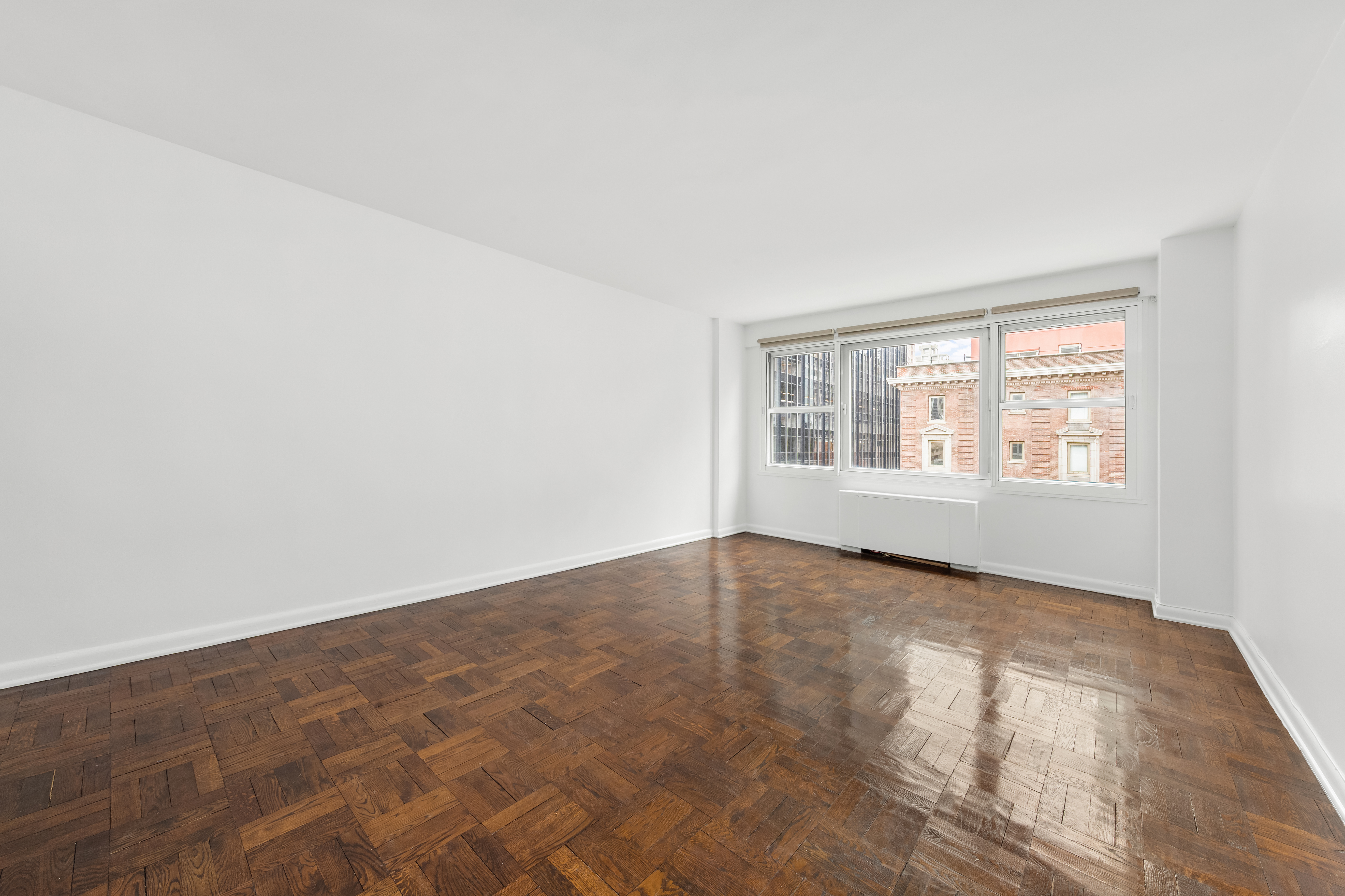 77 West 55th Street, Unit 17F Manhattan, NY 10019 - Photo 10 of 12 an empty room with wooden floor and windows