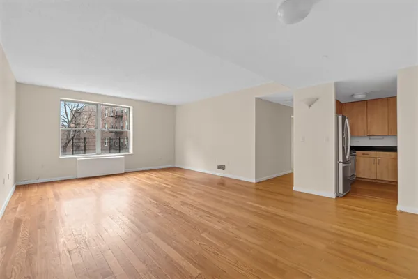 a view of an empty room with a window and wooden floor