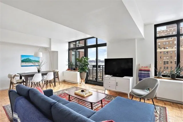 a living room with furniture a flat screen tv and a floor to ceiling window