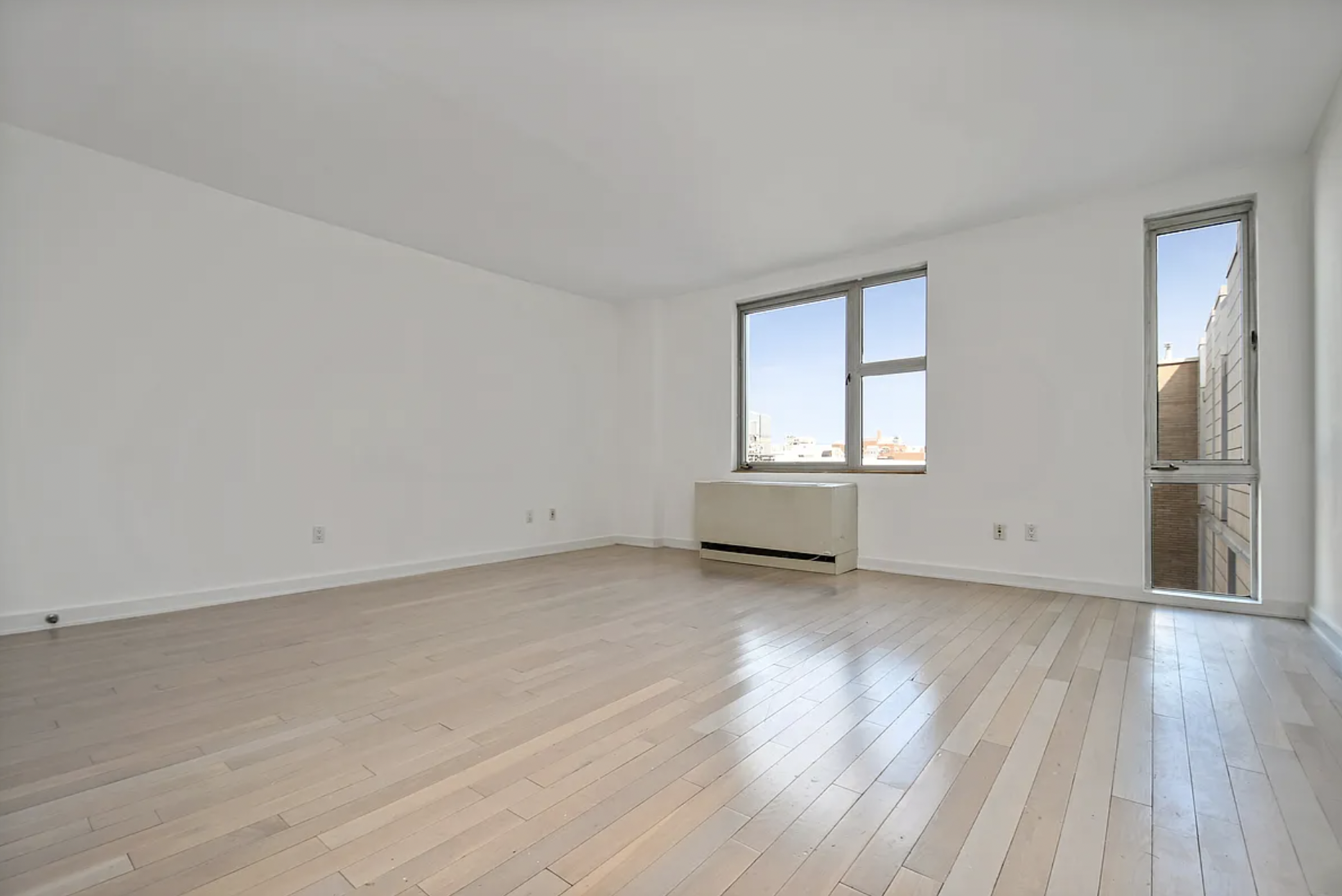 250 Bedford Avenue, Unit 308 Brooklyn, NY 11249 - Photo 1 of 8 an empty room with wooden floor and windows