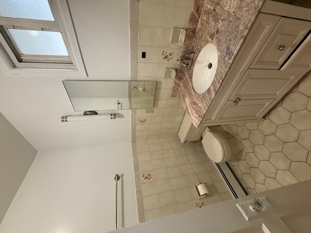 1587 East 18th Street, Unit 2 Brooklyn, NY 11230 - Photo 12 of 13 a bathroom with a granite countertop sink a toilet and a mirror