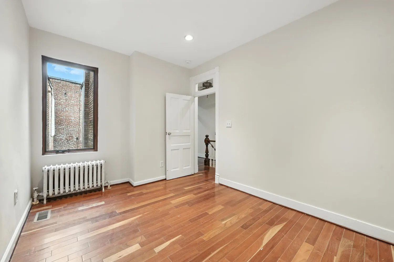 an empty room with wooden floor and a window