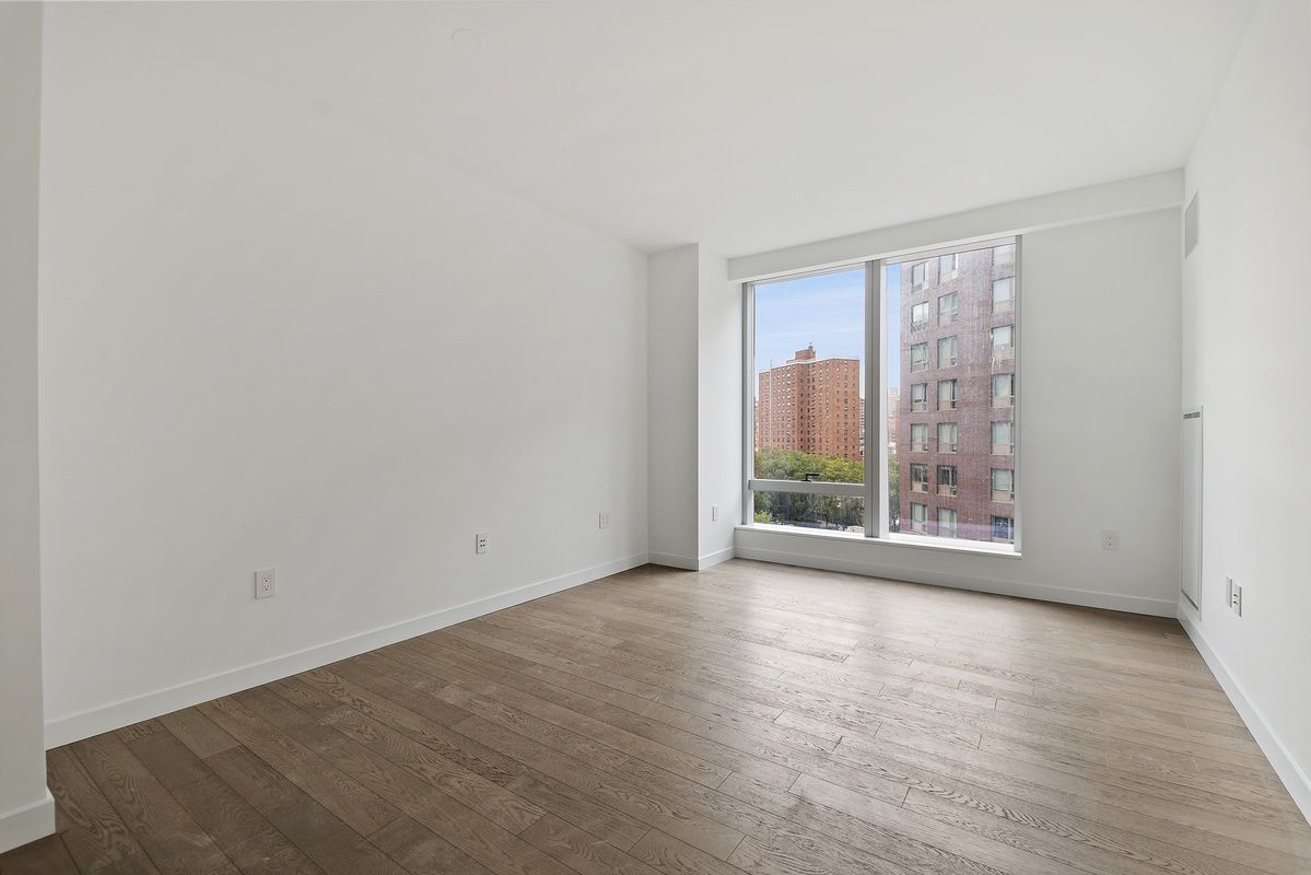 252 South Street, Unit 9J Manhattan, NY 10002 - Photo 1 of 19 a view of an empty room with wooden floor and a window