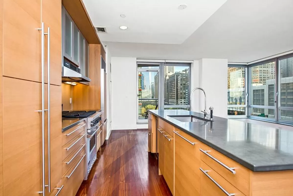 30 West Street, Unit 6B Manhattan, NY 10004 - Photo 3 of 13 a large kitchen with stainless steel appliances a large window a oven and a refrigerator