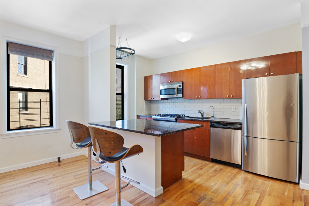 779 Riverside Drive, Unit A50 Manhattan, NY 10032 - Photo 3 of 14 a kitchen with stainless steel appliances granite countertop a refrigerator a stove a sink dishwasher and white cabinets with wooden floor