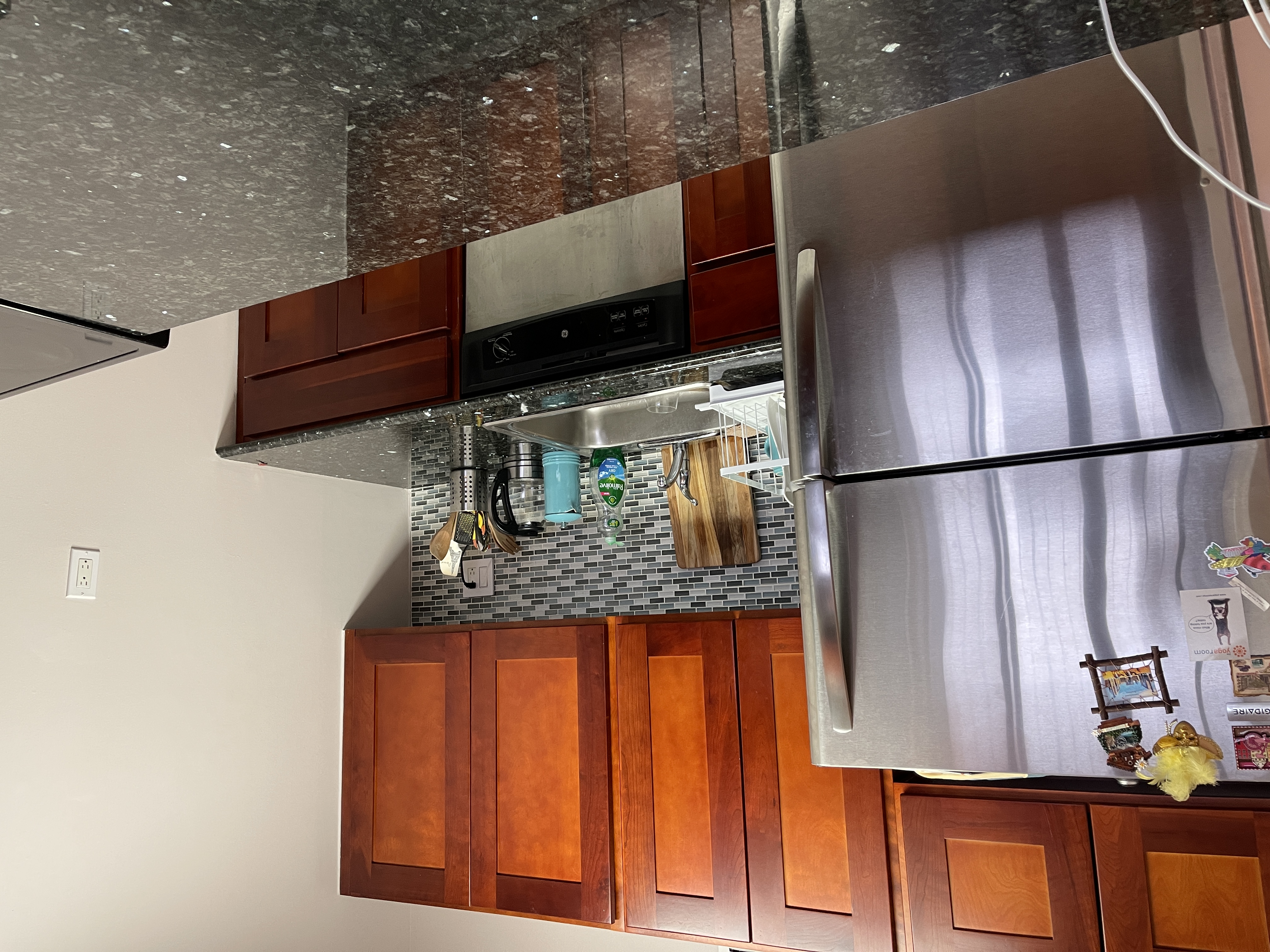 25-40 Shore Boulevard, Unit 8T Queens, NY 11102 - Photo 5 of 23 a kitchen with granite countertop wooden cabinets and a refrigerator