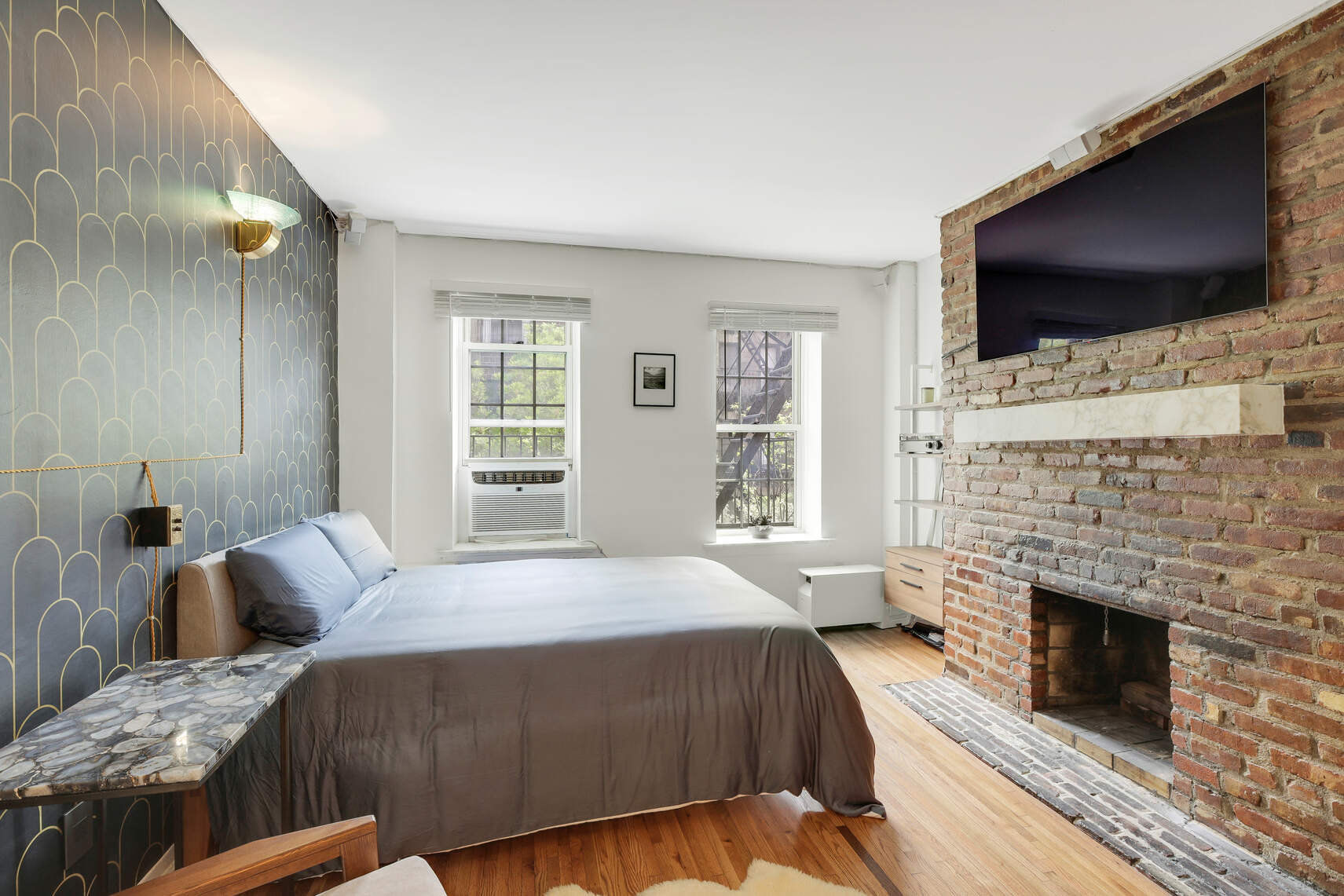210 East 21st Street, Unit 4E Manhattan, NY 10010 - Photo 1 of 9 a bedroom with a bed a flat screen tv and a fireplace