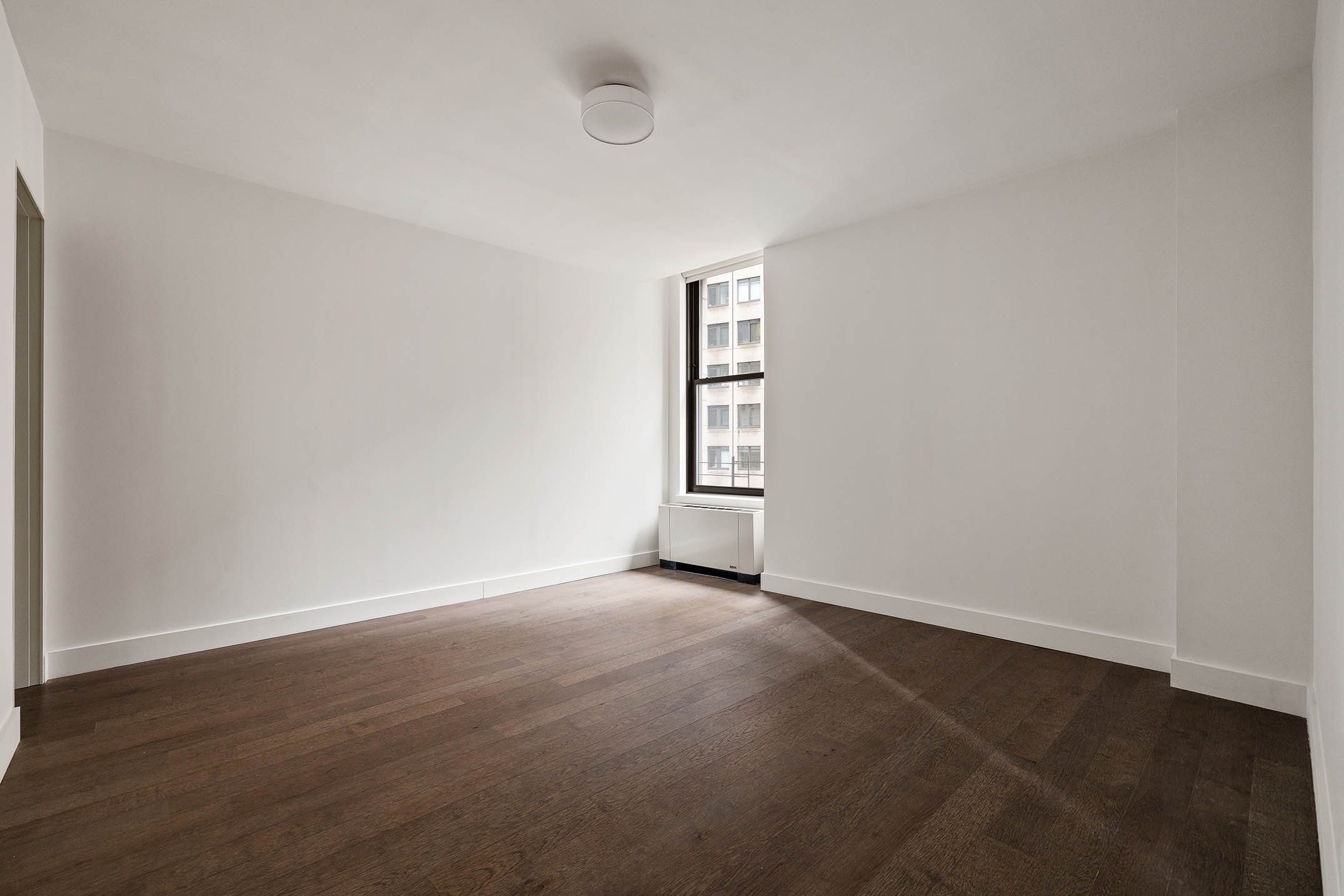 25 Broad Street, Unit 16I Manhattan, NY 10004 - Photo 9 of 23 an empty room with wooden floor and windows