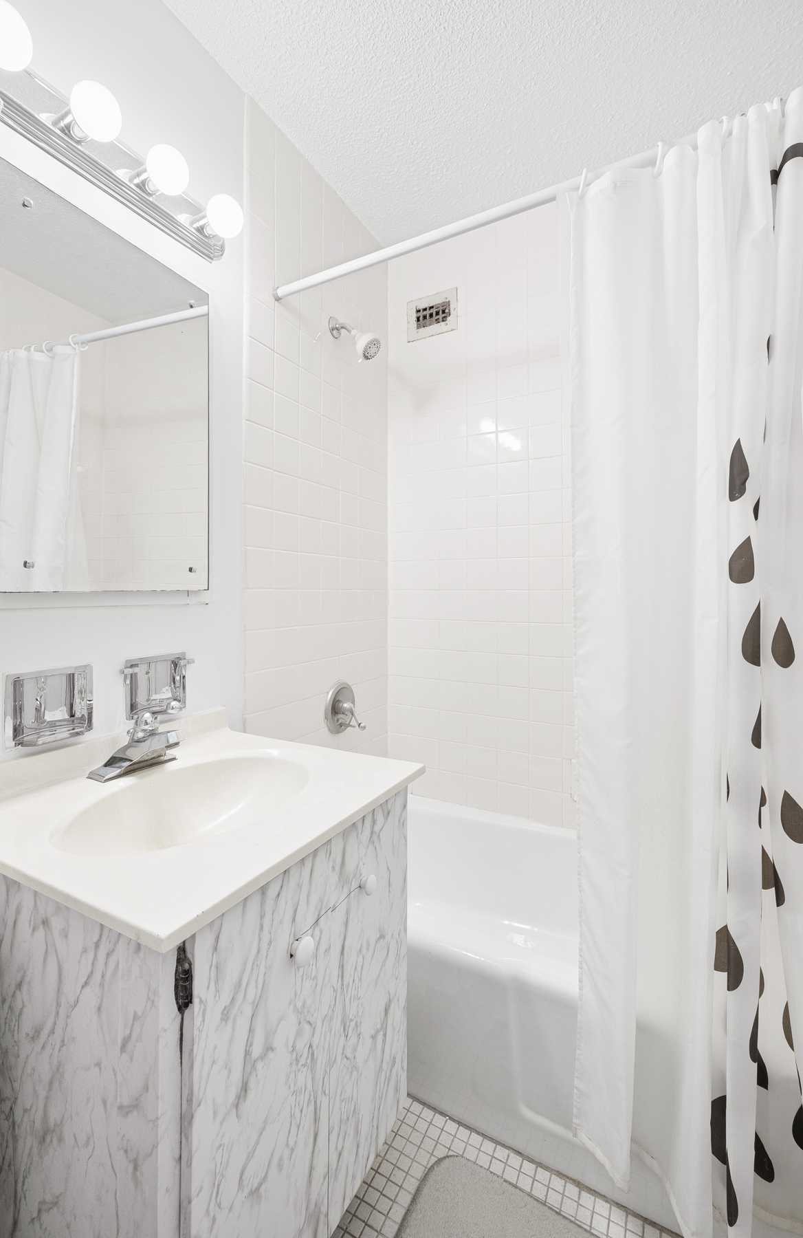 555 Main Street, Unit 512 Manhattan, NY 10044 - Photo 12 of 18 a bathroom with a granite countertop sink a mirror a shower and a bathtub