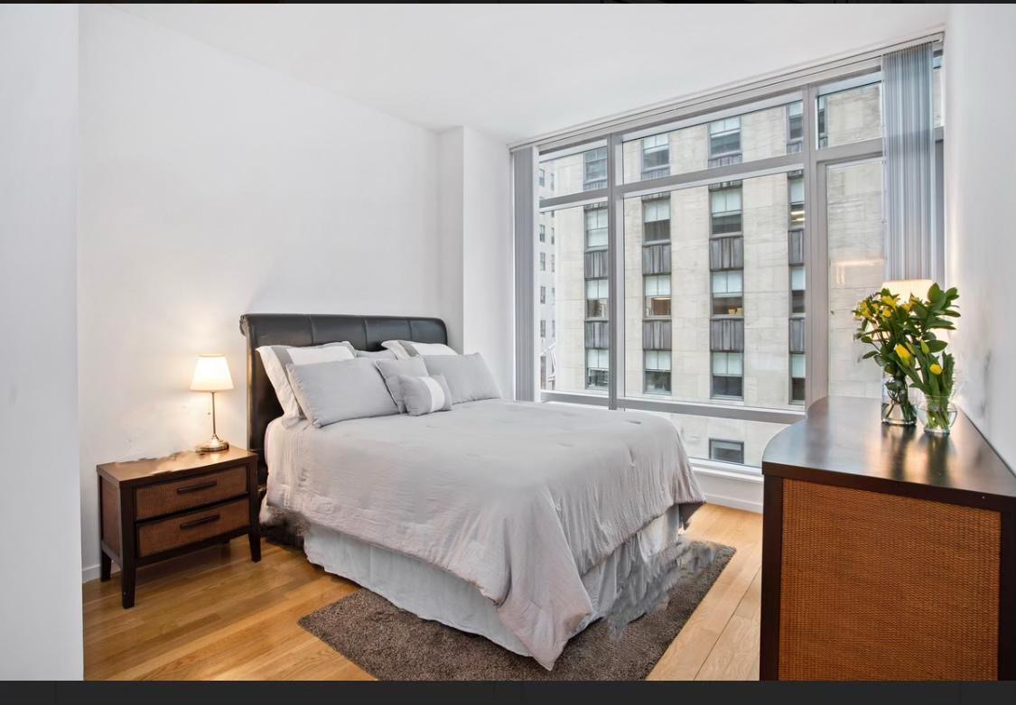 18 West 48th Street, Unit 3B Manhattan, NY 10036 - Photo 2 of 8 a bed sitting in a bedroom next to a window