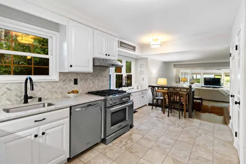 a kitchen with kitchen island granite countertop a sink stove and cabinets