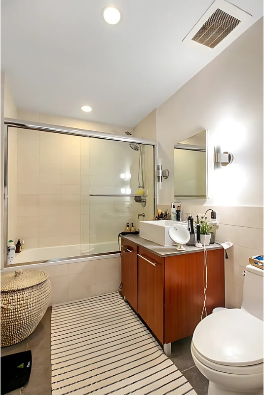 517 West 46th Street, Unit 307 Manhattan, NY 10036 - Photo 8 of 10 a bathroom with a granite countertop sink toilet a mirror and bathtub