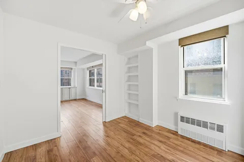 a view of empty room with wooden floor and fan