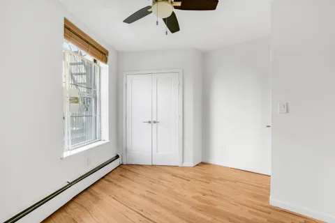 a view of an empty room with a window and wooden floor