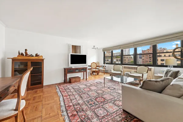 a living room with furniture a flat screen tv and floor to ceiling window