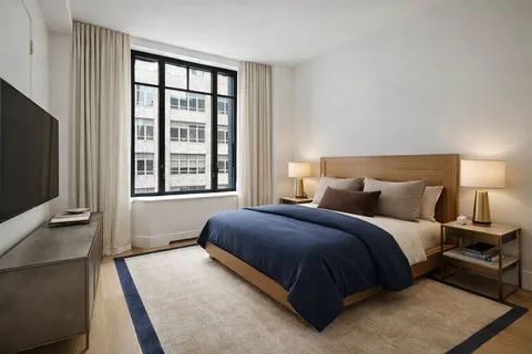 a bedroom with a bed and a flat tv screen on a dresser
