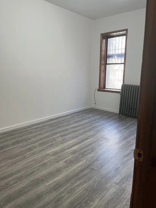 571 Nostrand Avenue, Unit 3R Brooklyn, NY 11216 - Photo 2 of 7 a view of an empty room with wooden floor and a window