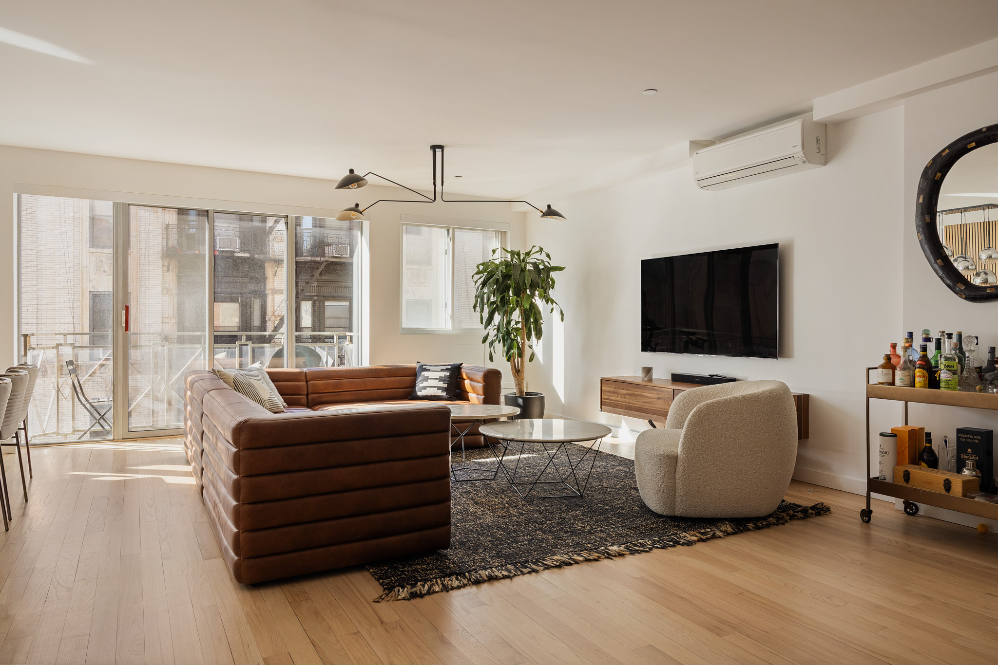 182 Mulberry Street, Unit 4 Manhattan, NY 10012 - Photo 2 of 13 a living room with furniture a flat screen tv and a floor to ceiling window
